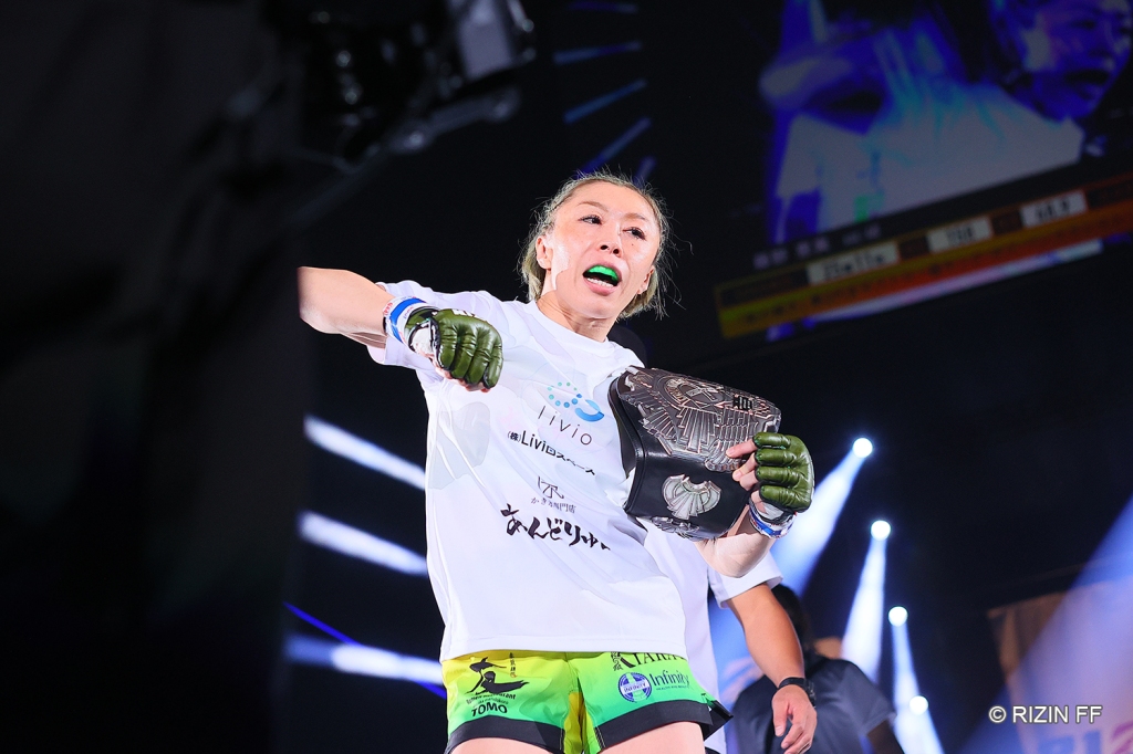 Emi Fujino walks down a ramp while holding her Queen of Pancrase Strawweight Championship.